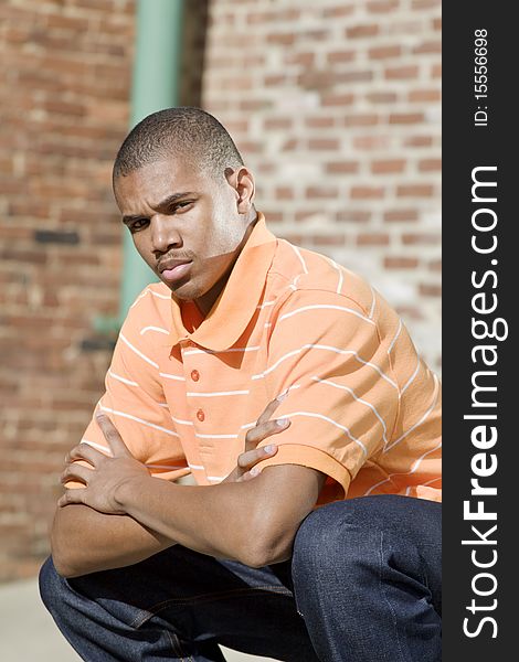 Handsome African American male model posed in front of a brick background. Handsome African American male model posed in front of a brick background.