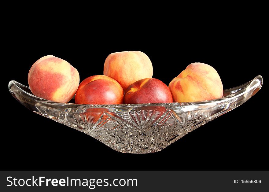 Big, ripe nectarines and peaches in a crystal vase for fruits