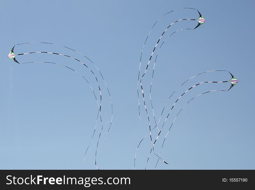 Three identical kites flying and turning in the blue sky