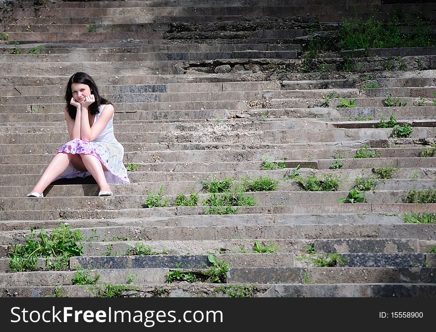 The girl sits on an old ladder and looks in the cam. The girl sits on an old ladder and looks in the cam