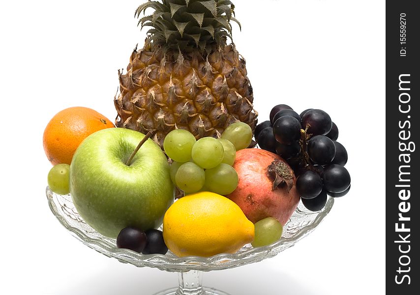 Group of different fruits in a glass vase on a white background