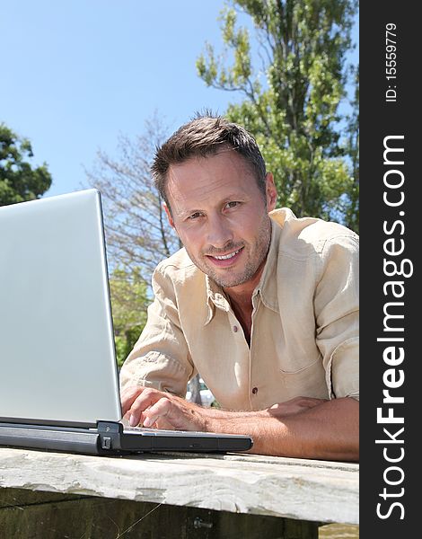 Man using laptop computer on a pontoon. Man using laptop computer on a pontoon