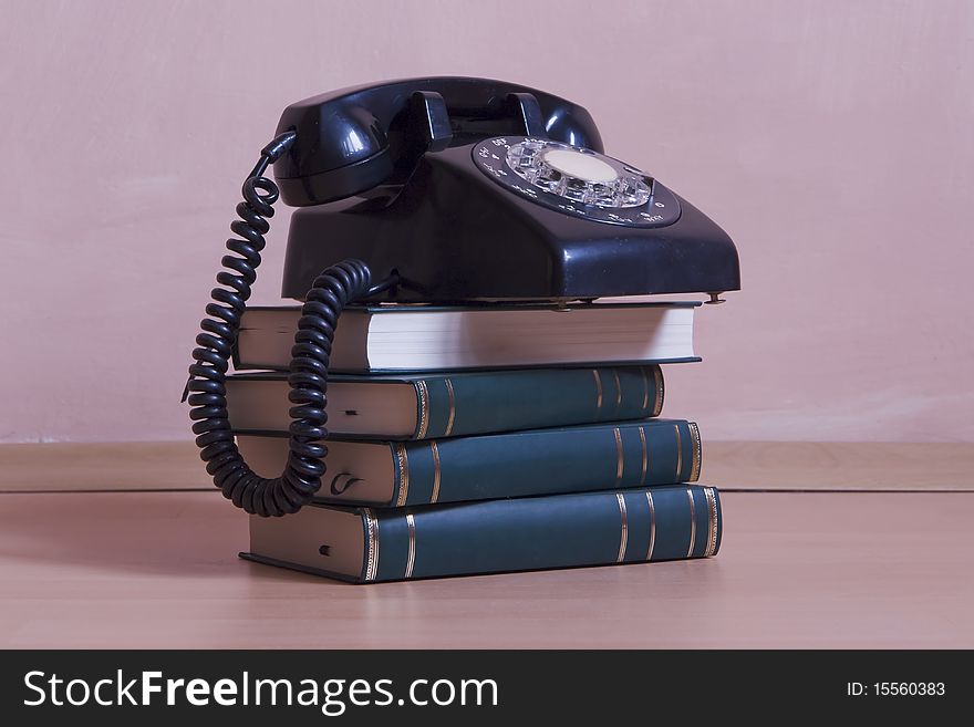 Small stack of books with vintage telephone on top