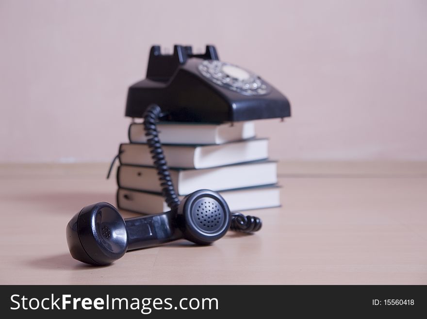 Small stack of books with vintage telephone on top, focus in front