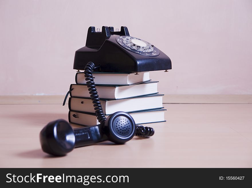 Small stack of books with vintage telephone on top, focus on background