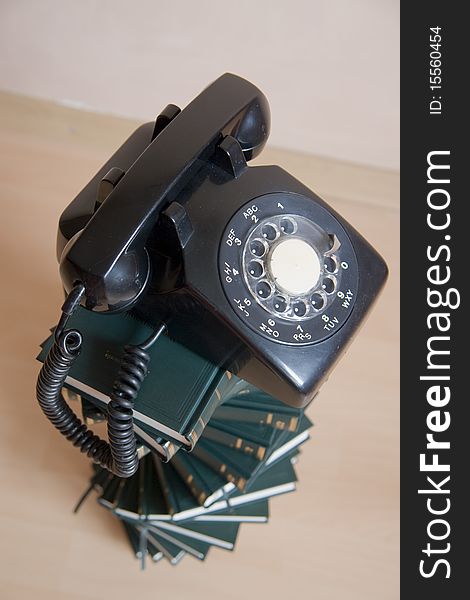 Small stack of books with vintage telephone on top, focus on top