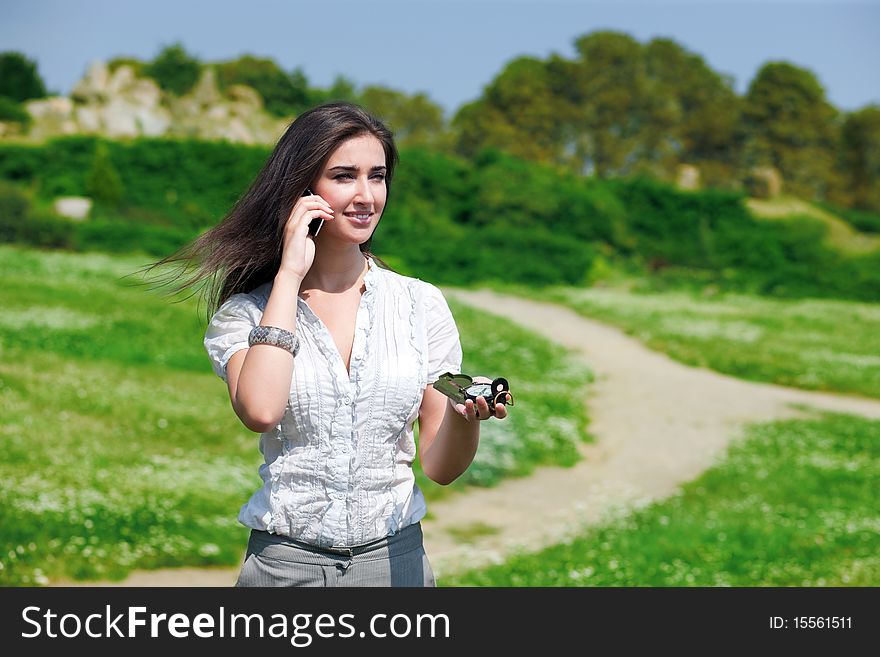 Portrait of young pretty woman speaking on phone with compass in hand