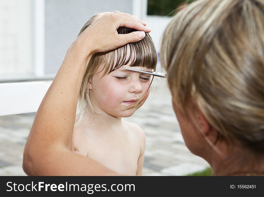 Woman cutting young girls hair outdoor. Woman cutting young girls hair outdoor