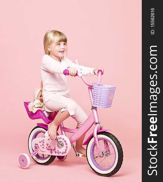 Young girl on her bike towards pink background