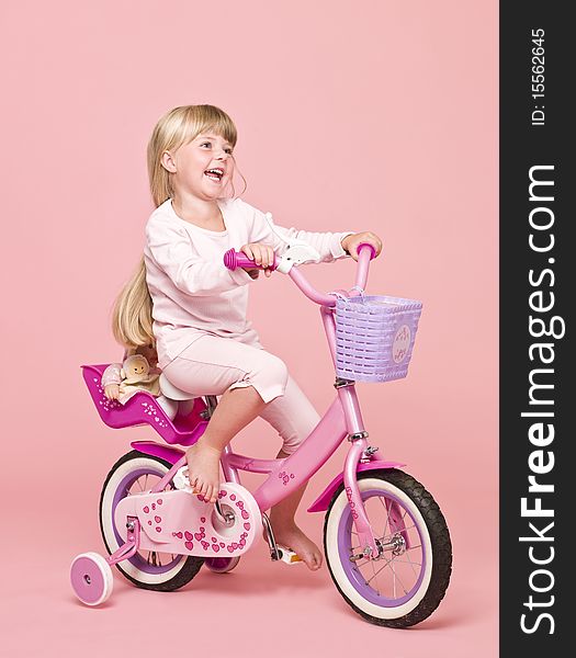 Young girl on her bike towards pink background