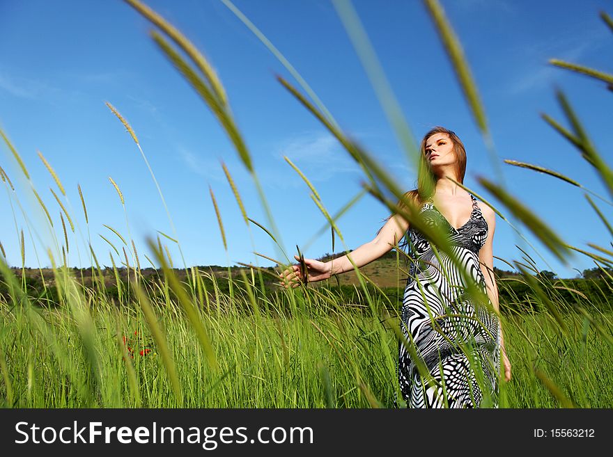 Young beautiful woman standing on the green field. Young beautiful woman standing on the green field