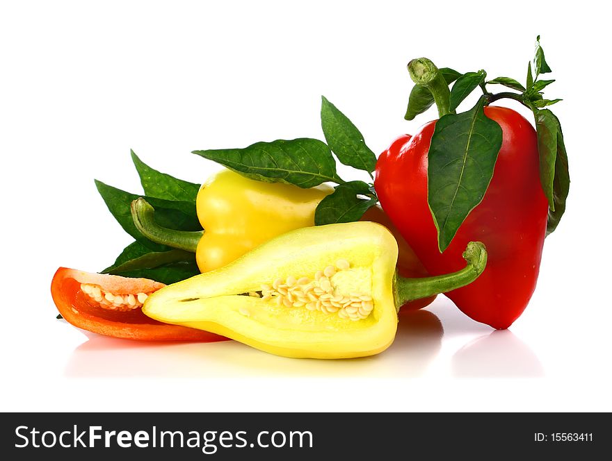 Red and yellow cut pepper and green leaf isolated on white background