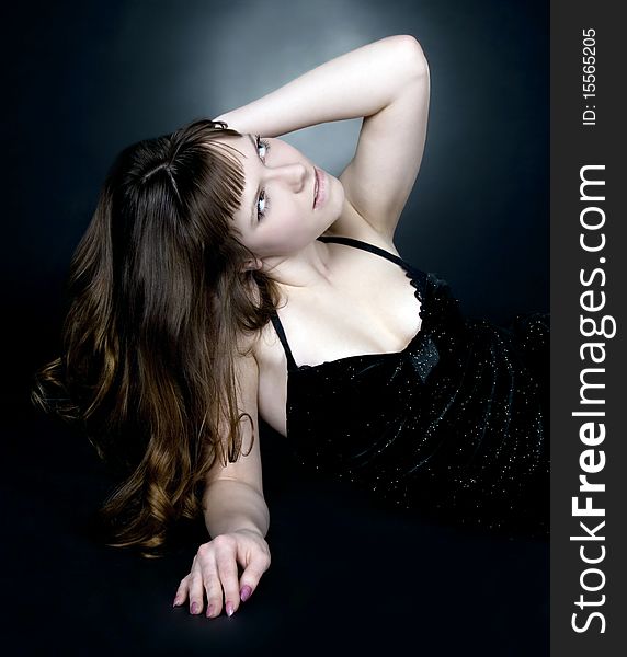 Beautiful brunette girl posing in studio on dark background