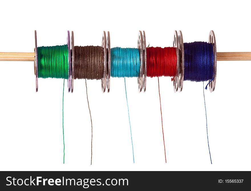 A row of five coloured cotton bobbins against a white background colored. A row of five coloured cotton bobbins against a white background colored