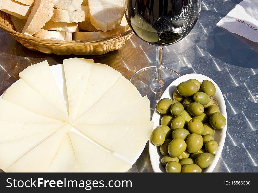 Delicious dish consisting of olives, cheese, bread and a glass of red vine. Delicious dish consisting of olives, cheese, bread and a glass of red vine.