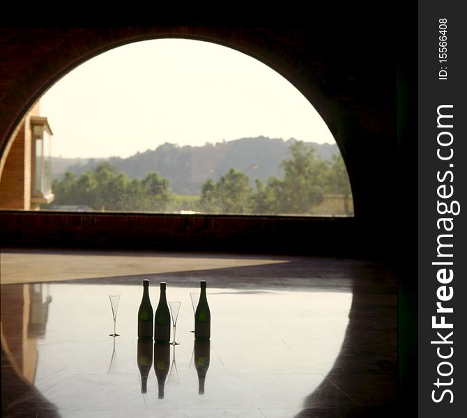 Three bottles of champagne and glasses standing in sun floated windows half.