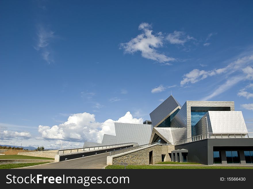 Futuristic building with reflection roof in front of a bright blue sky.