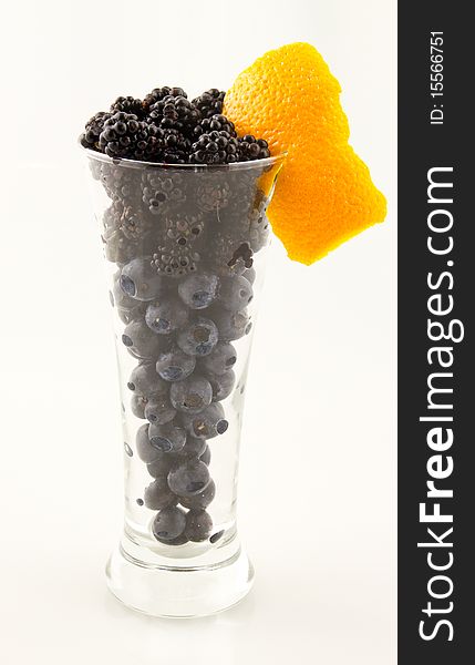 This is an image of blueberries and blackberries in a tall glass with a twist. This is an image of blueberries and blackberries in a tall glass with a twist.