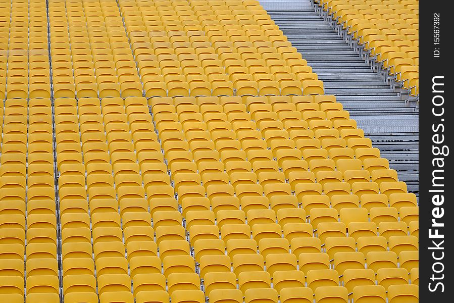 Rows of bright yellow modular tiered spectator seats and stairs by the side. Rows of bright yellow modular tiered spectator seats and stairs by the side.