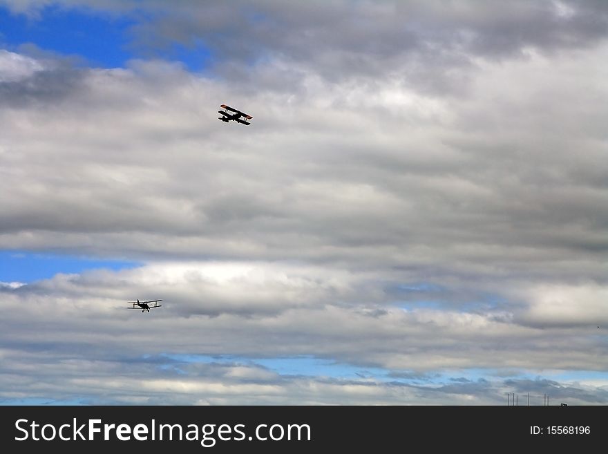 Silhouettes of two airplanes flying in a cloudy sky
