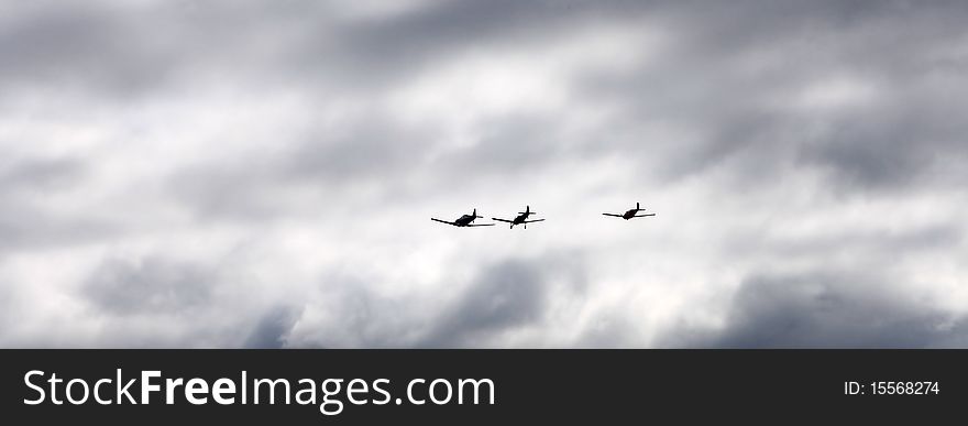 Silhouettes of three airplanes flying into dramatic clouds