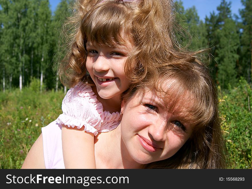 The laughing beautiful girl embraces the woman in the summer in park. The laughing beautiful girl embraces the woman in the summer in park