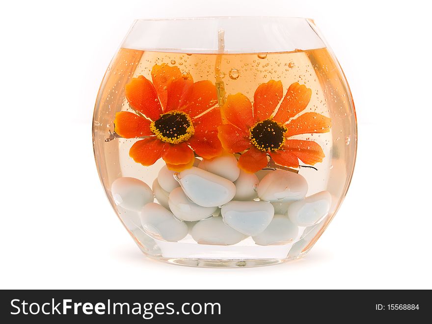 Aromatic candle in the form of an aquarium with orange flowers and white pebbles inside, on a white background