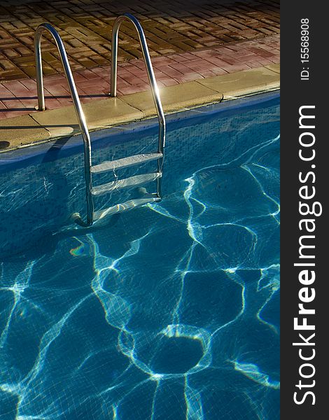 Rails of steps glint in the sunshine at the outdoor holiday pool. Rails of steps glint in the sunshine at the outdoor holiday pool