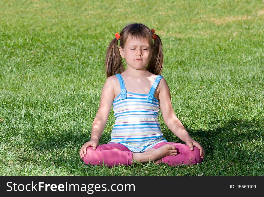 Little child sit and meditate in asana on grass