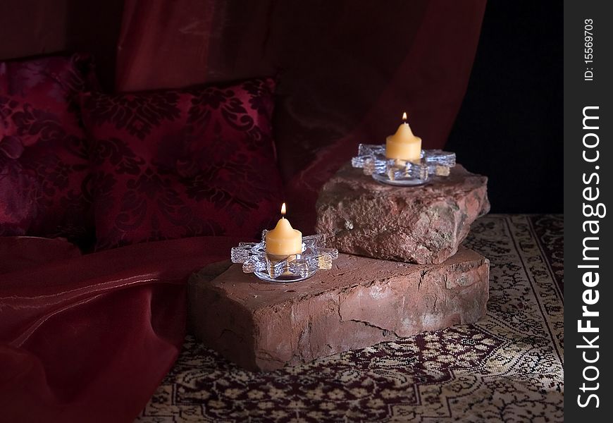 The photo shows a still life with two candles on a brick. The photo shows a still life with two candles on a brick