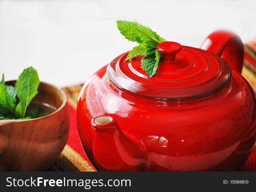 Red teapot with mint tea and a wooden tea cup