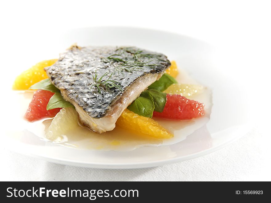 Delicious fried fish fillet with orange, grapefruit, lemon and fresh basil