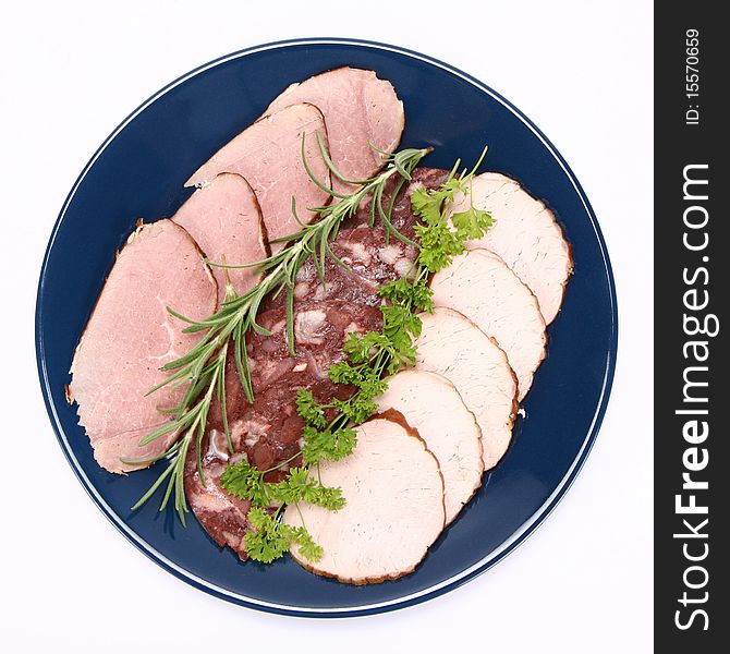 Plate of assorted cold cuts (ham, sirloin, headcheese) decorated with rosemary and parsley