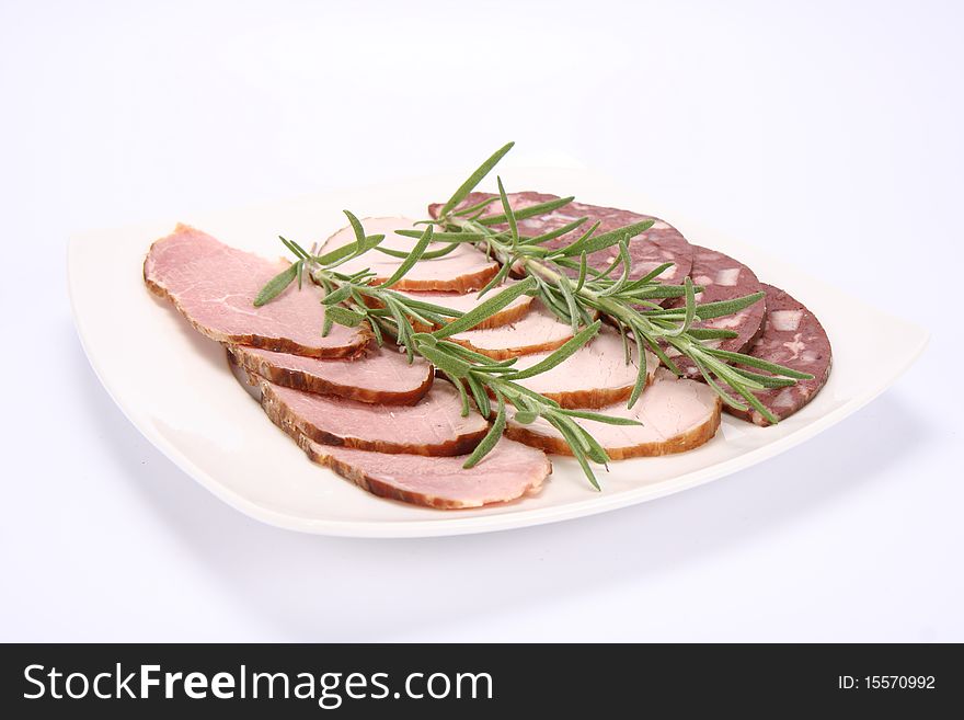 Plate of assorted cold cuts (ham, sirloin, headcheese) decorated with rosemary