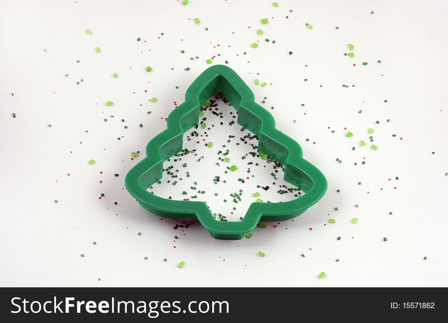 Christmas tree cookie cutter with red and green sprinkles laid out on a white background. Christmas tree cookie cutter with red and green sprinkles laid out on a white background