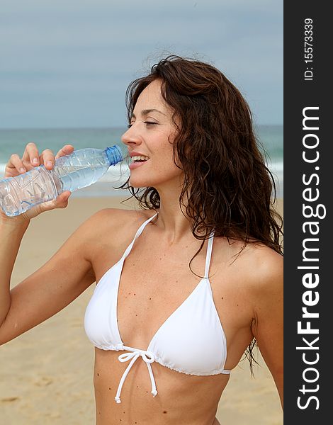Beautiful woman drinking water at the beach. Beautiful woman drinking water at the beach