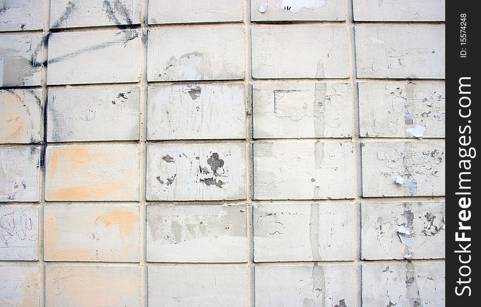 Dirty white brick wall. It can be seen fragments of ads and inscriptions. Dirty white brick wall. It can be seen fragments of ads and inscriptions.