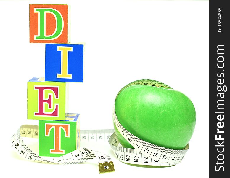 Tape measure wrapped around green apple and cubes with letters - diet