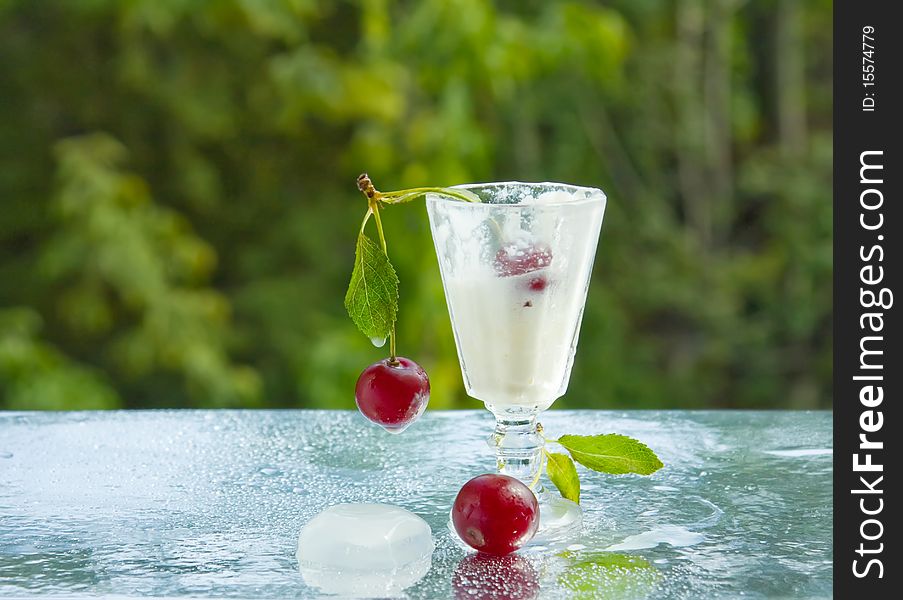 A small cup of cold cream and cherries. A small cup of cold cream and cherries