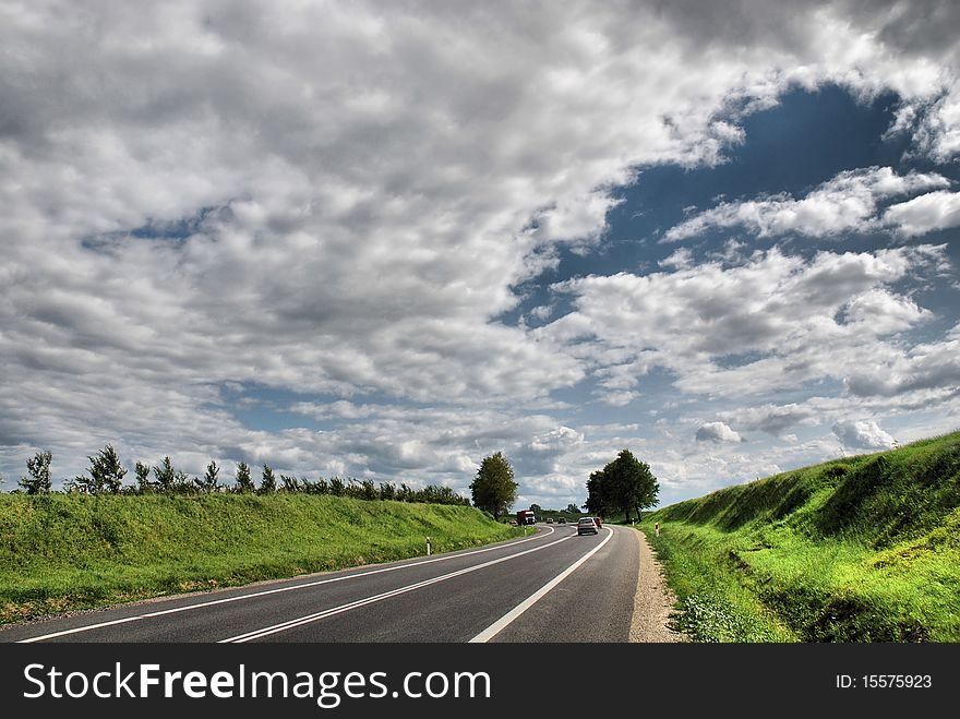 A deserted country road running through some green fields