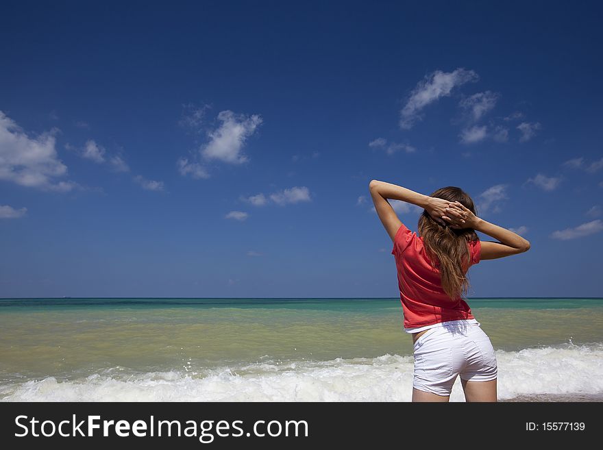 Young female looking at sea with her hands up getting a breath of sea air