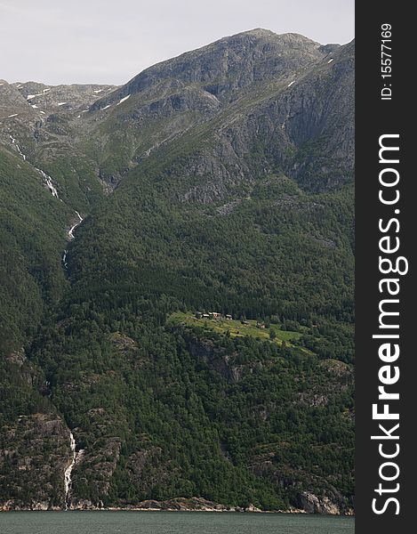 A waterfall cascades into the Hardangerfjord in Norway. A waterfall cascades into the Hardangerfjord in Norway