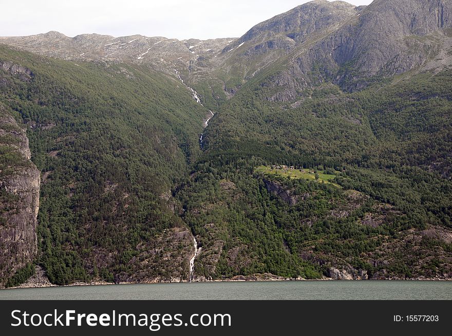 A waterfall cascades into the Hardangerfjord in Norway. A waterfall cascades into the Hardangerfjord in Norway