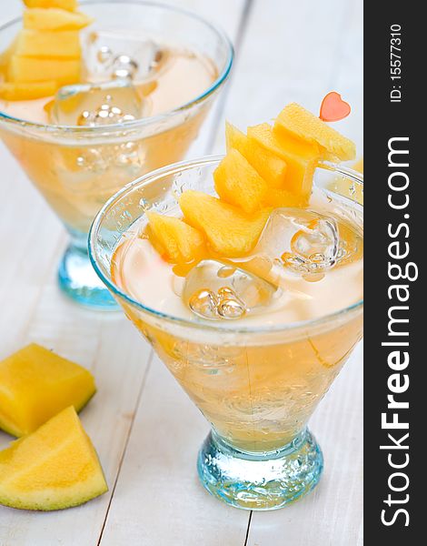 Cocktail with mango fruit on wooden table top