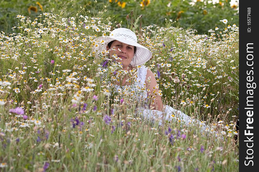 Lady in white dress and hat on a field with camomiles. Lady in white dress and hat on a field with camomiles