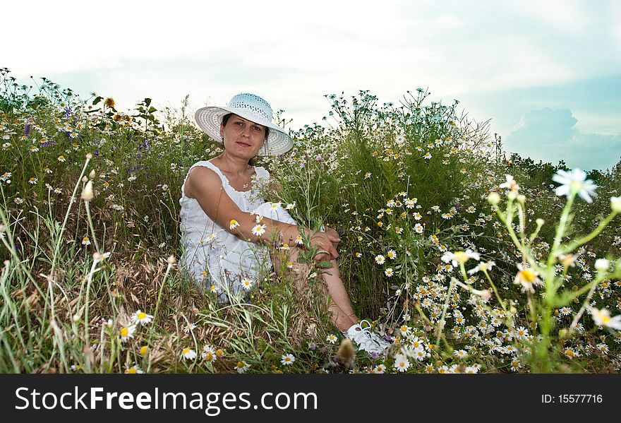 Lady in white dress and hat on a field with camomiles. Lady in white dress and hat on a field with camomiles