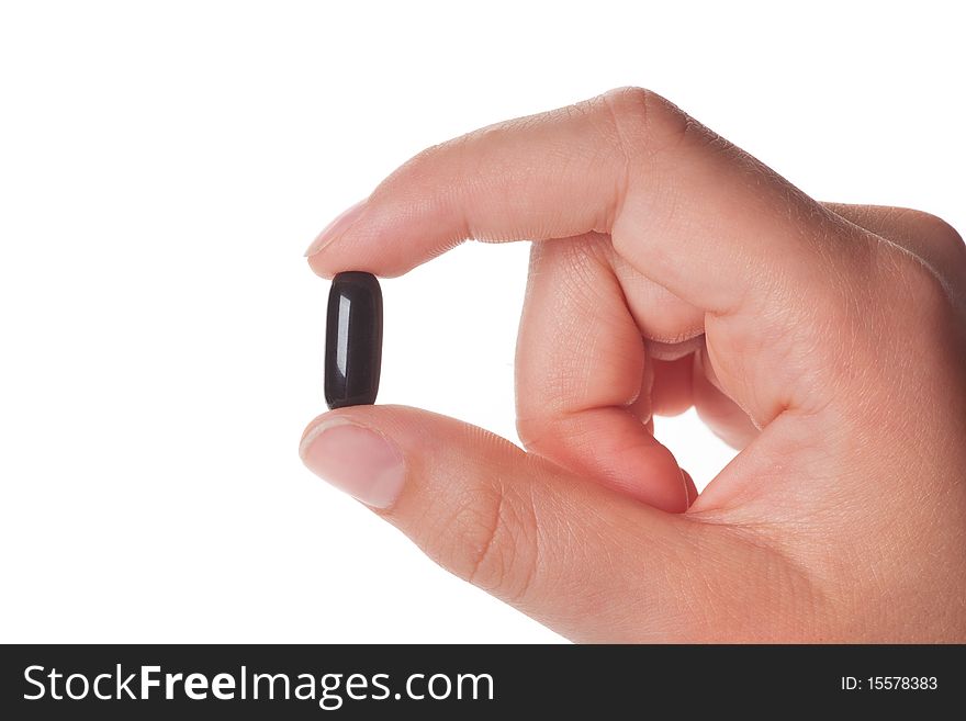 Female hand holding a black capsule, isolated on white