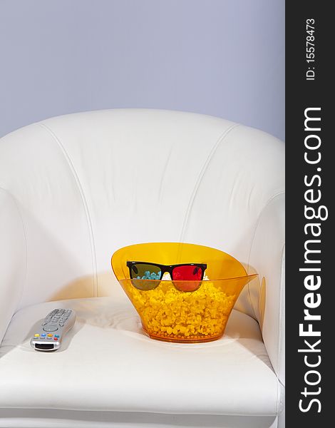 3D glasses, popcorn and a remote control on a sofa. 3D glasses, popcorn and a remote control on a sofa.