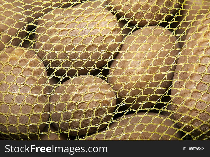 A yellow mesh bag of russet potatoes.