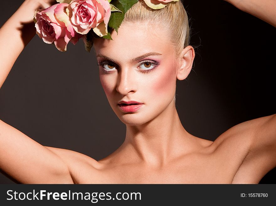 Portrait of beautiful blonde with a wreath of flowers on her head on the black background